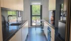 Moderne Galley-Küche mit weißen Hochglanzfronten, schwarzer Arbeitsplatte und Fensterfront in Luxus-Apartment Palma