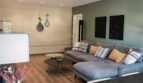Helles Wohnzimmer mit grauer Eckcouch, grüner Akzentwand und modernem Esstisch in Palma-Apartment