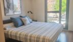 Helles Schlafzimmer mit Doppelbett, Holzboden, Deckenventilator und großem Fenster mit Stadtblick in Palma