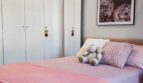 Helles Schlafzimmer mit rosa Bettwäsche, weißem Einbauschrank und Blumenkunstdruck in Luxus-Apartment Palma