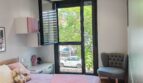 Helles Kinderzimmer mit rosa Bettwäsche, Deckenventilator und großem Fenster mit Grünblick in Palma-Apartment