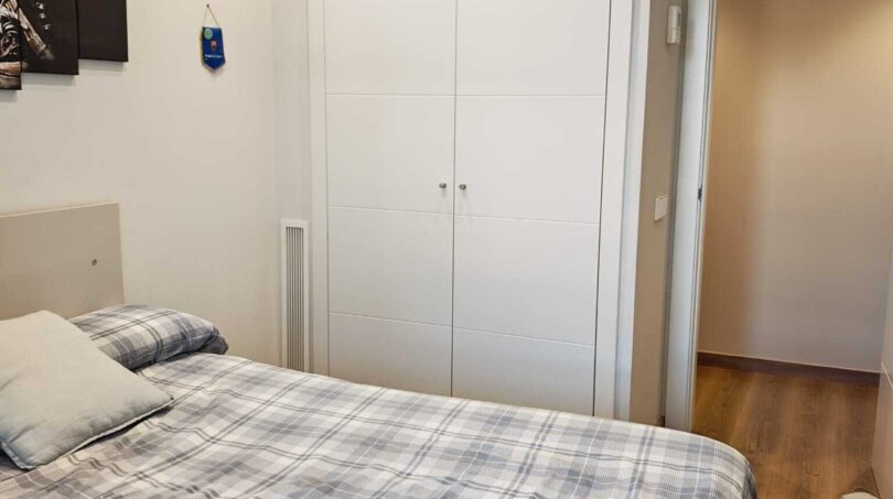 Helles Schlafzimmer mit blau-weißer Bettwäsche, weißem Einbauschrank und Holzboden im Luxus-Apartment Palma