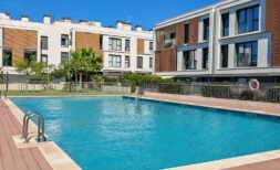 Gemeinschaftspool mit Holzterrasse der Luxusresidenz in Palma de Mallorca, umgeben von modernen Apartmentgebäuden.