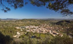 Panoramic view of Mancor de la Vall with natural stone houses, surrounded by green hills and wide landscape.