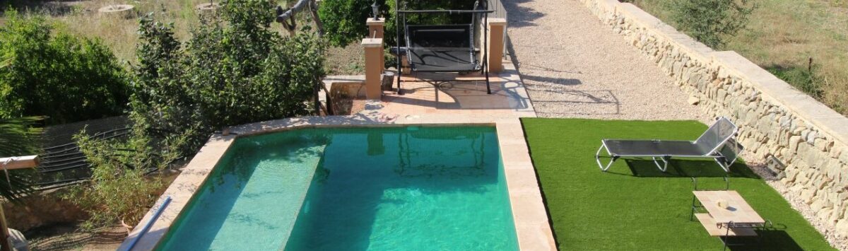 Finca Llucmajor: Pool with turquoise water, sun loungers on artificial grass and garden facility with natural stone wall.