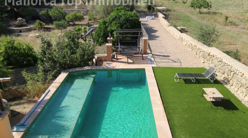 Finca Llucmajor: Pool with turquoise water, sun loungers on artificial grass and garden facility with natural stone wall.