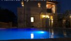 Finca Llucmajor: Beleuchteter Pool bei Nacht vor zweistöckigem Natursteinhaus mit warmem Lichtschein.