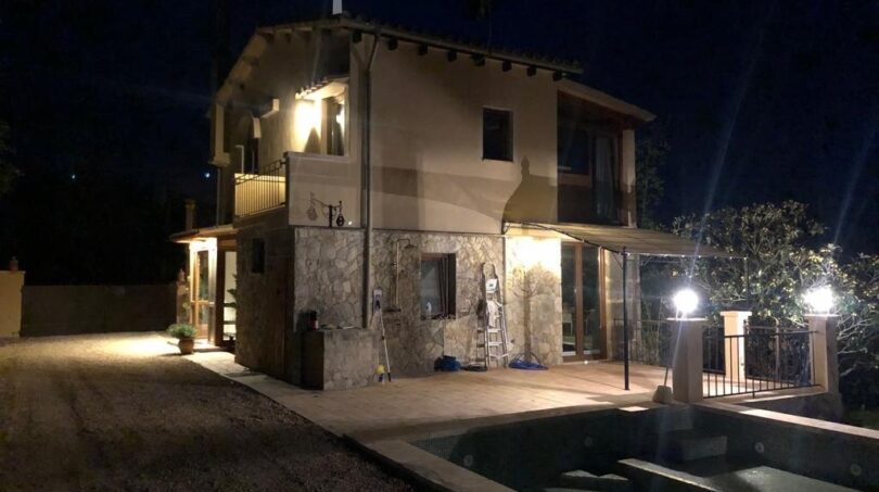 Finca Llucmajor bei Nacht: Beleuchtete Naturstein-Villa mit Pool, Terrasse und Pergola, eingebettet in die Natur.