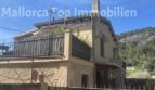 Außenansicht der Finca in Llucmajor mit Terrasse, Natursteindetails und Blick auf bewaldete Berglandschaft.