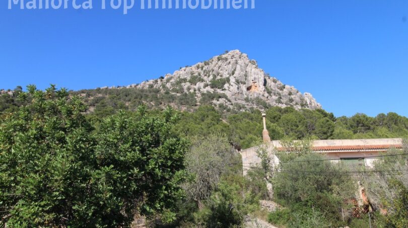 Außenansicht der Finca in Llucmajor mit Blick auf den markanten Hexenberg und umgebende Natur.