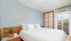 Helles Schlafzimmer mit Doppelbett, Holzmöbeln, Klimaanlage und Balkonzugang mit Naturblick