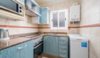 Küche mit blauen Holzfronten, Granitarbeitsplatte, Einbauofen, Mikrowelle und Waschmaschine im Apartment Palma