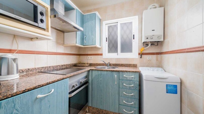Küche mit blauen Holzfronten, Granitarbeitsplatte, Einbauofen, Mikrowelle und Waschmaschine im Apartment Palma