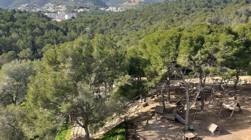 Panoramablick auf Spielplatz, Pinienwald und Berge von Palma de Mallorca mit blauem Himmel.