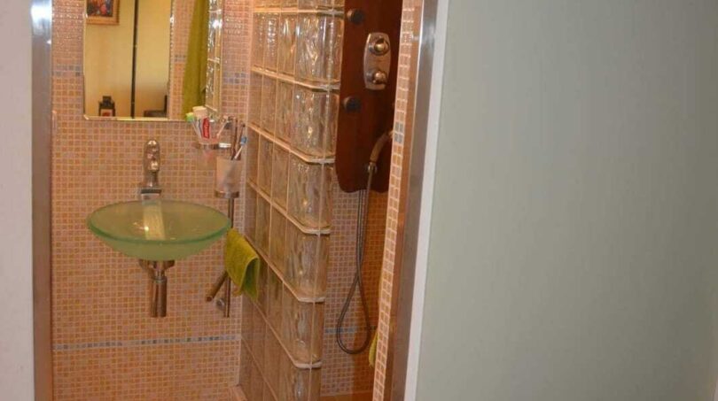 Modernes Bad mit Glasbausteindusche, grünem Glasbecken-Waschbecken und Mosaikfliesen in einem Apartment in Palma.