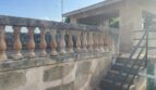 Terrassenbrüstung mit Steinbaluster der mediterranen Villa in Porto Cristo, Außentreppe aus Metall sichtbar