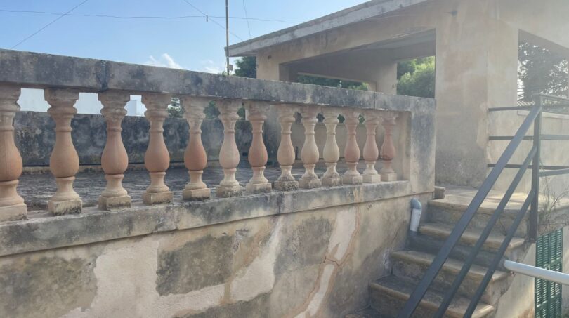 Terrassenbrüstung mit Steinbaluster der mediterranen Villa in Porto Cristo, Außentreppe aus Metall sichtbar