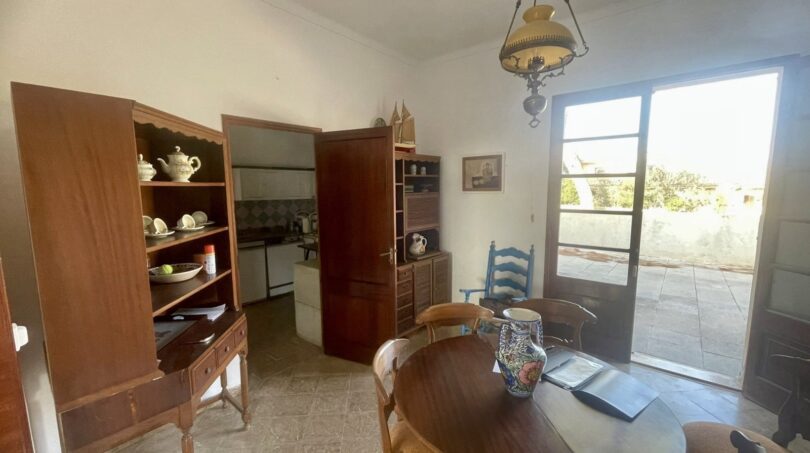 Esszimmer mit rundem Holztisch, Vitrinenschrank und Zugang zur Terrasse in mediterraner Villa Porto Cristo
