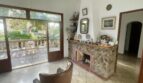 Wohnzimmer der mediterranen Villa in Porto Cristo mit Natursteinkamin, Lederstuhl und Terrassenzugang zum Garten.