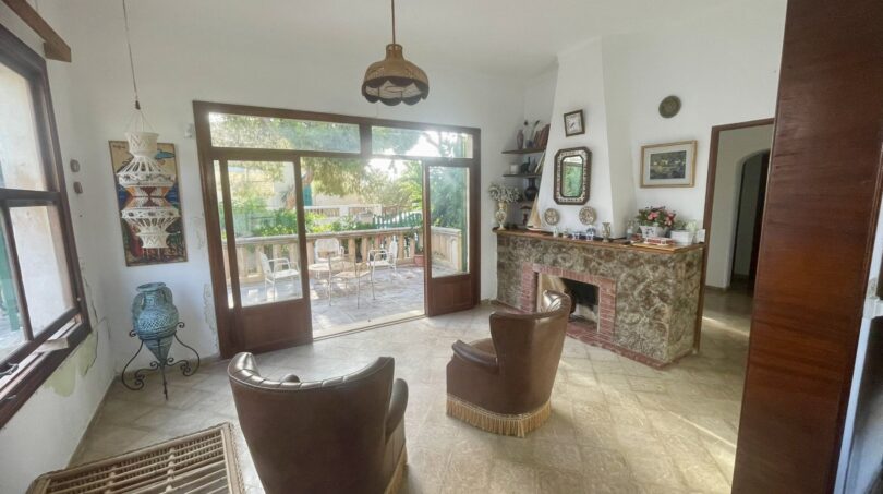 Wohnzimmer der mediterranen Villa mit Kamin, Ledersesseln und Terrassenzugang zum Garten in Porto Cristo