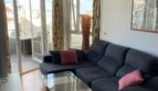 Helles Wohnzimmer mit dunkelblauem Ecksofa, Glasstisch und großen Fenstern mit Stadtblick über Palma