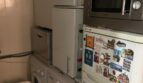 Cuarto de servicio estrecho con lavadora, secadora, refrigerador y microondas en apartamento del casco antiguo de Palma
