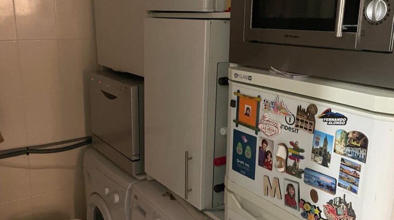 Cuarto de servicio estrecho con lavadora, secadora, refrigerador y microondas en apartamento del casco antiguo de Palma