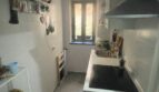 Cocina estrecha del apartamento del casco antiguo de Palma con placa de cocción, fregadero, campana extractora y ventana al patio interior.