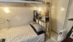 Pequeño dormitorio con cama individual, litera, techo de vigas de madera y armario empotrado en apartamento del casco antiguo de Palma