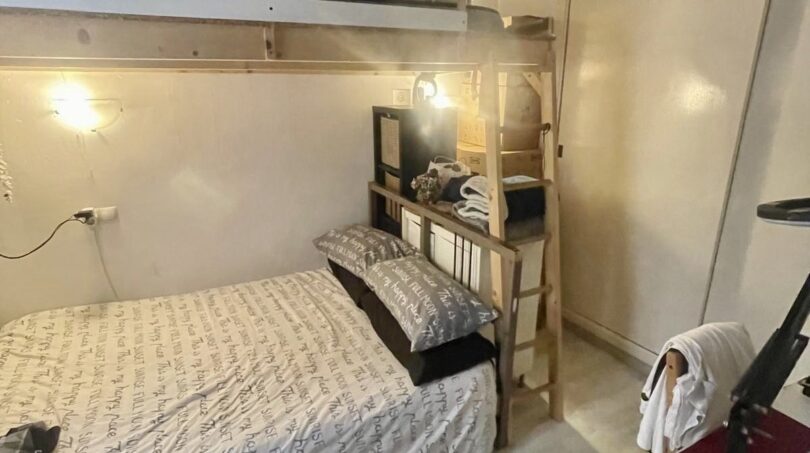Pequeño dormitorio con cama individual, litera, techo de vigas de madera y armario empotrado en apartamento del casco antiguo de Palma