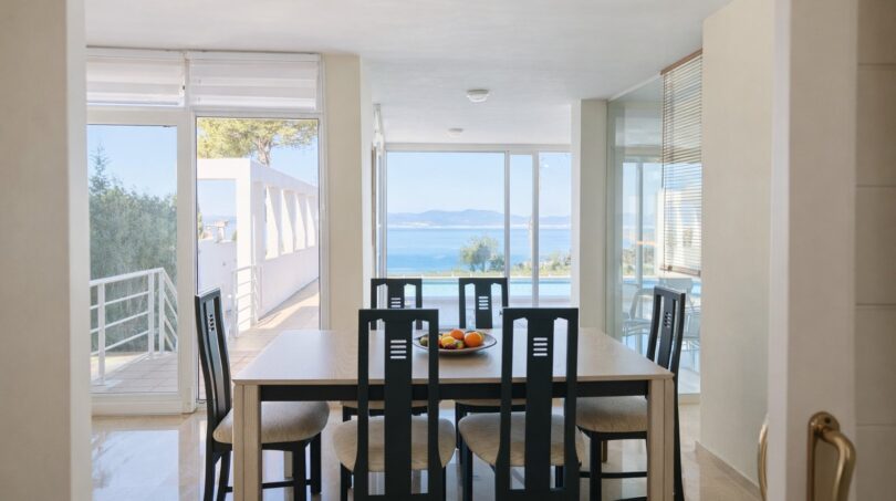 Helles Esszimmer der First-Line-Villa in Llucmajor mit Meerblick, Pool und großen Panoramafenstern.