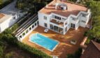 Luftaufnahme einer weißen Luxusvilla mit Pool und Terrasse in Llucmajor, umgeben von Grünflächen.