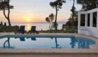 Außenpool der First-Line-Villa in Llucmajor mit Meerblick und romantischem Sonnenuntergang über dem Mittelmeer.