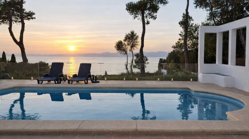 Außenpool der First-Line-Villa in Llucmajor mit Meerblick und romantischem Sonnenuntergang über dem Mittelmeer.