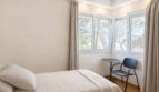 Helles Schlafzimmer der First-Line-Villa in Llucmajor mit Doppelbett, Schreibtisch und großen Fenstern zum Garten.