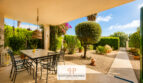 Überdachte Terrasse mit Esstisch, gepflegtem Garten und mediteraner Bepflanzung des Luxus-Chalets in Cala Murada.