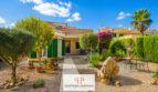 Außenansicht Luxus-Chalet Cala Murada: mediterrane Villa mit grünen Fensterläden, Steinweg und gepflegtem Steingarten.