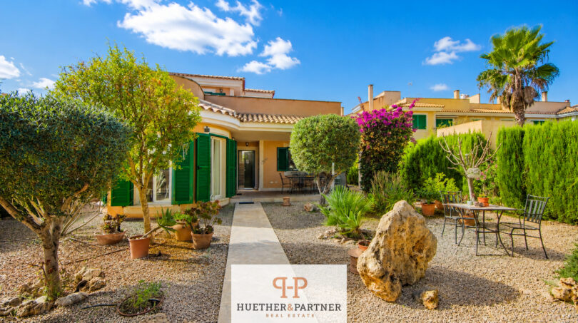 Außenansicht Luxus-Chalet Cala Murada: mediterrane Villa mit grünen Fensterläden, Steinweg und gepflegtem Steingarten.