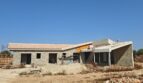 Estructura en bruto de una finca moderna en Vilafranca de Bonany con muros de piedra natural y techo de tejas mediterráneo en construcción.