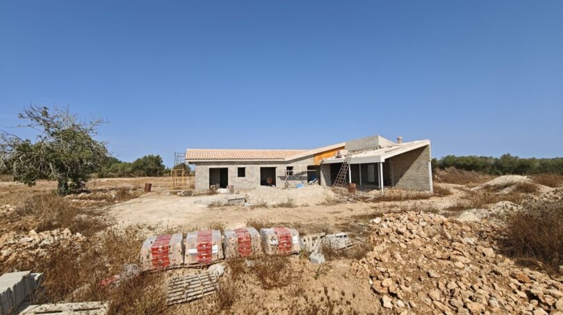 Estructura en bruto de una finca moderna en Vilafranca de Bonany con techo plano y materiales de construcción en la propiedad.