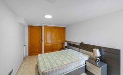 Dormitorio del dúplex en Portocolom con cama de matrimonio, cabecero moderno y puertas de armario de madera