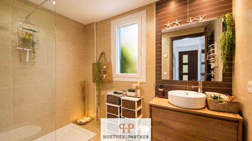 Modernes Badezimmer im Luxus-Chalet Cala Murada mit Glasdusche, Holzwaschtisch und maritimer Dekoration.