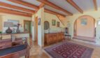 Geräumiger Eingangsbereich der Finca in Campanet mit Holzbalkendecke, Terrakottaboden und antikem Sideboard.