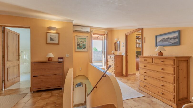 Heller Treppenbereich der Finca in Campanet mit Holzkommoden, Klimaanlage und Zugang zu mehreren Räumen.