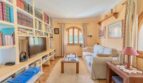 Gemütliches Wohnzimmer der Finca in Campanet mit Bücherregal, TV, weißem Sofa und Bogenfenster.