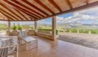 Überdachte Terrasse der Finca Campanet mit Holzbalken, Lounge-Möbeln und Panoramablick auf Berge.