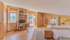 Helles Schlafzimmer der Finca in Campanet mit Holzmöbeln, TV, Bücherregal und Terrassenzugang.