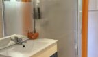 Modernes Badezimmer mit ebenerdiger Dusche und praktischem Waschtisch mit Stauraum