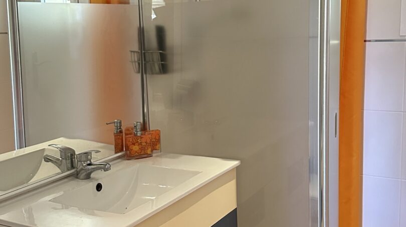 Modernes Badezimmer mit ebenerdiger Dusche und praktischem Waschtisch mit Stauraum