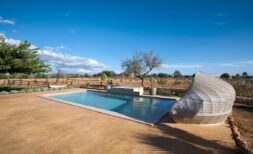 Außenpool der Finca in Campos mit Natursteinteasse, modernem Loungemöbel und Blick auf die Landschaft.
